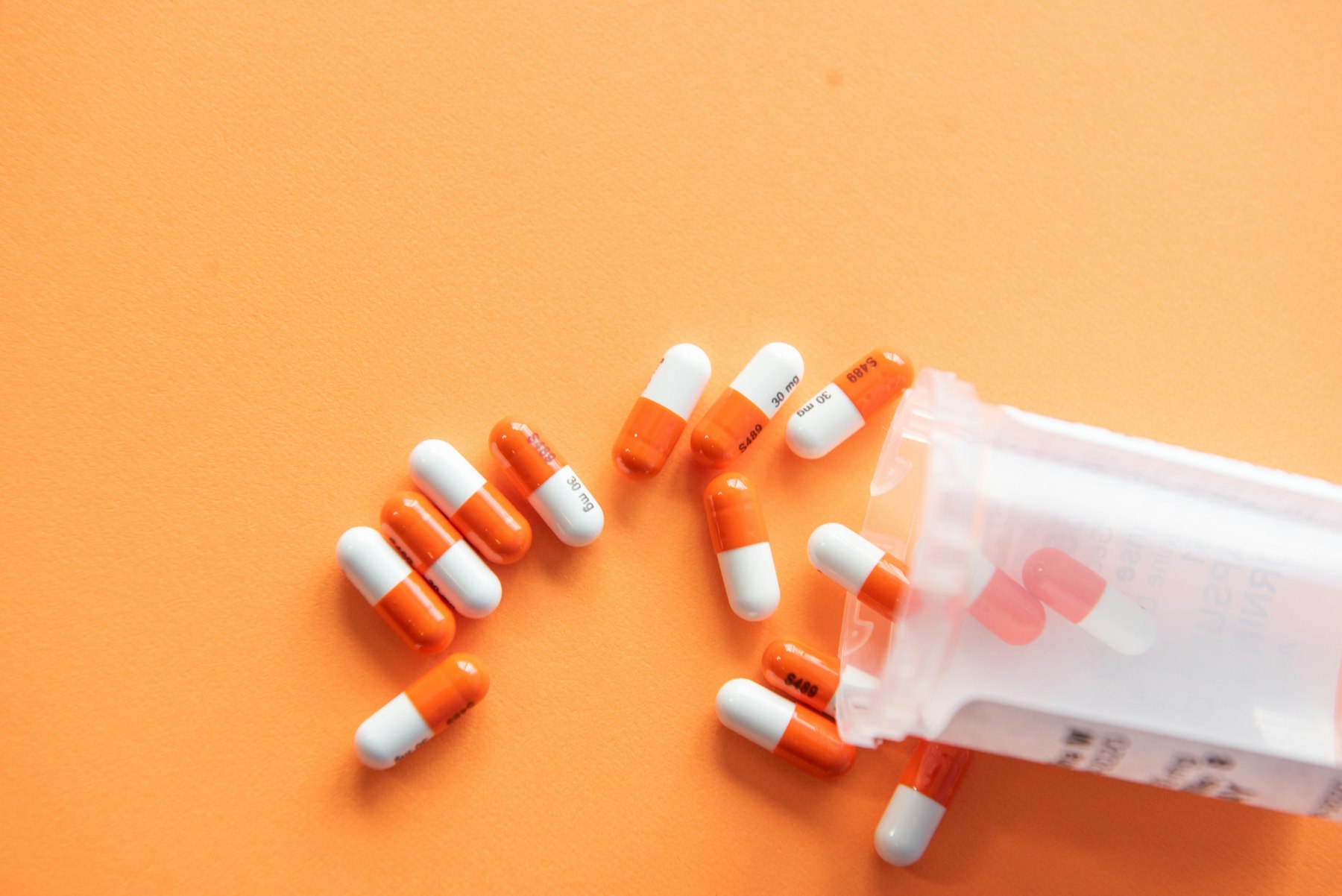 Prescription pills and bottle on an orange background